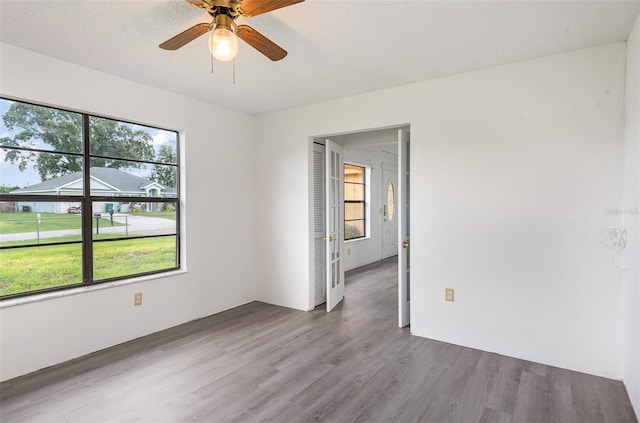 unfurnished room with a textured ceiling, wood-type flooring, and ceiling fan