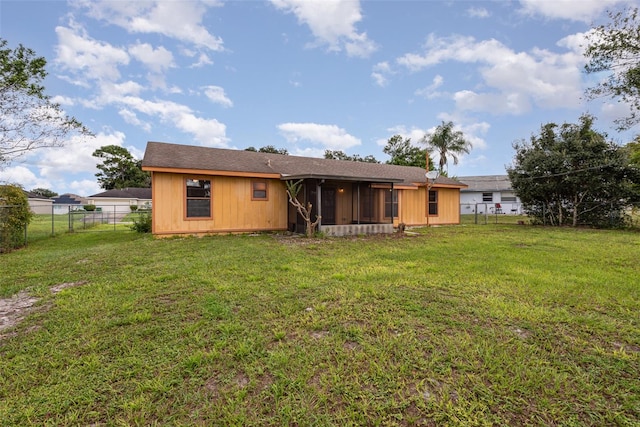 rear view of house featuring a sunroom and a lawn