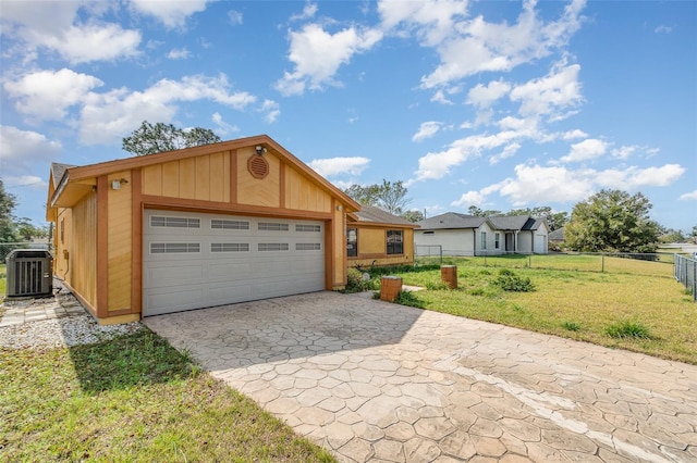 view of front of property featuring a garage, a front yard, and central air condition unit