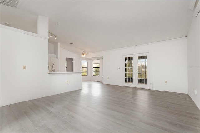 unfurnished living room featuring hardwood / wood-style floors, rail lighting, lofted ceiling, ceiling fan, and french doors