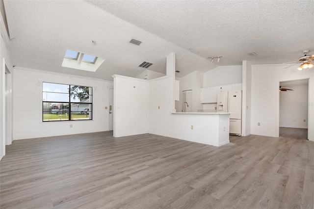 3186 Mapleshade St, Deltona, FL 32738 - unfurnished living room featuring vaulted ceiling, a textured ceiling, a sink, a skylight, and light wood-type flooring