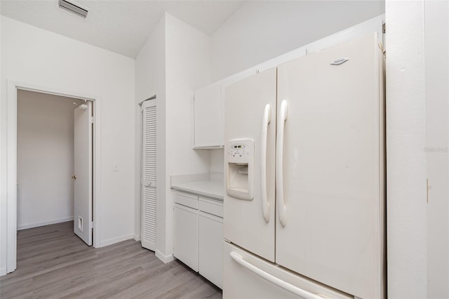 3186 Mapleshade St, Deltona, FL 32738 - kitchen with white fridge with ice dispenser, light wood-style flooring, white cabinets, light countertops, and baseboards