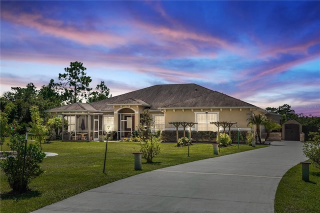 view of front of home featuring a lawn, a sunroom, and an outbuilding