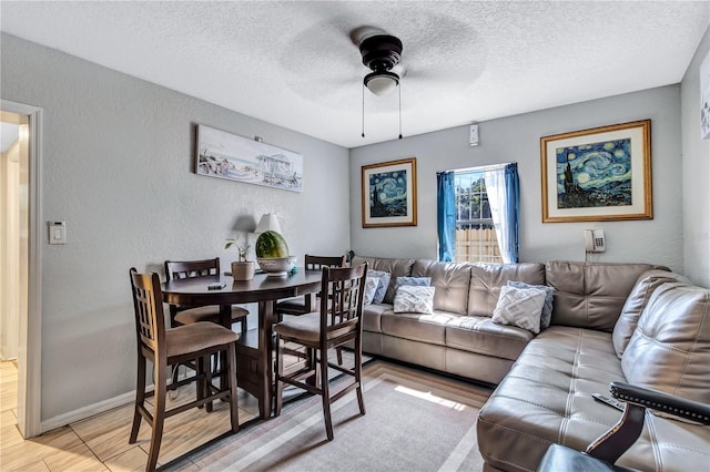 living room with light wood-type flooring, a textured ceiling, and ceiling fan