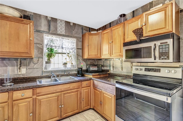 kitchen with stainless steel appliances, sink, and dark stone counters