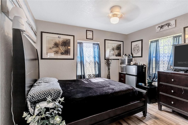 bedroom with light hardwood / wood-style floors, ceiling fan, and a textured ceiling