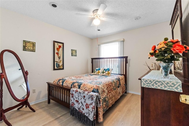 bedroom featuring ceiling fan, a textured ceiling, and light hardwood / wood-style floors