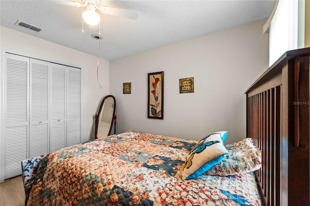 carpeted bedroom with a textured ceiling, ceiling fan, and a closet