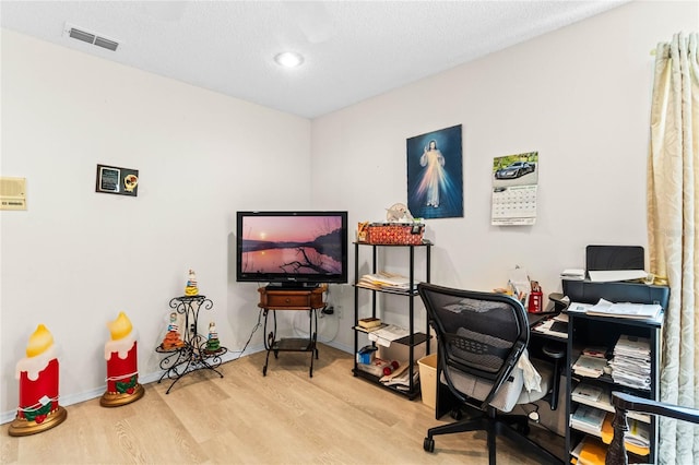 home office with light hardwood / wood-style floors and a textured ceiling