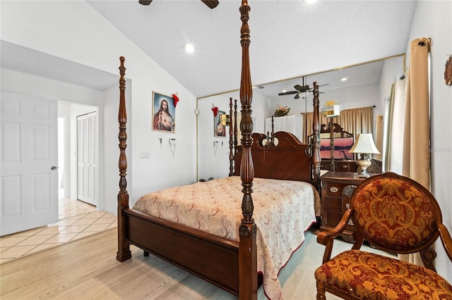 bedroom featuring light wood-type flooring, lofted ceiling, and a textured ceiling