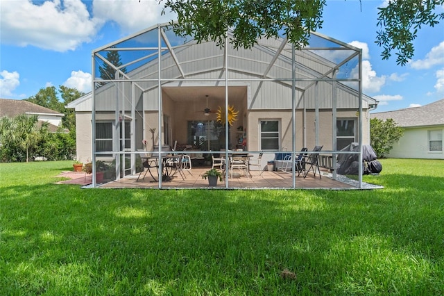 back of house featuring ceiling fan, a yard, glass enclosure, and a patio