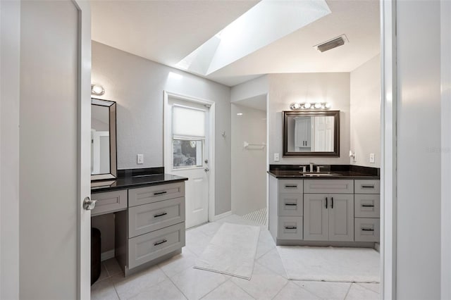 bathroom with vanity, a skylight, and tile patterned floors