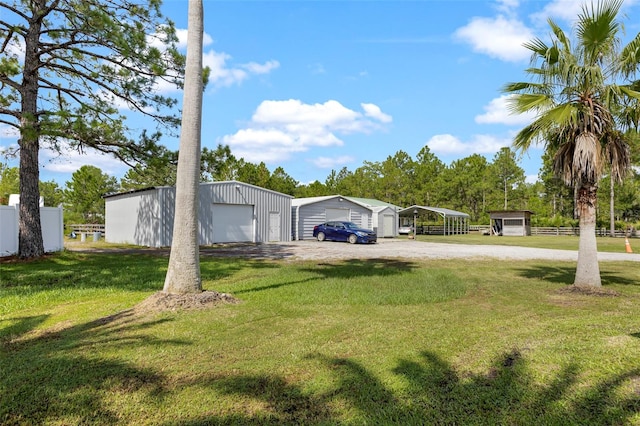 view of yard featuring a garage, a carport, and an outbuilding