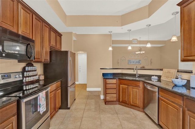 kitchen featuring dark stone counters, light tile patterned flooring, sink, hanging light fixtures, and appliances with stainless steel finishes