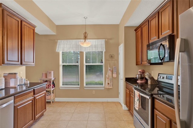 kitchen featuring appliances with stainless steel finishes, hanging light fixtures, and light tile patterned floors