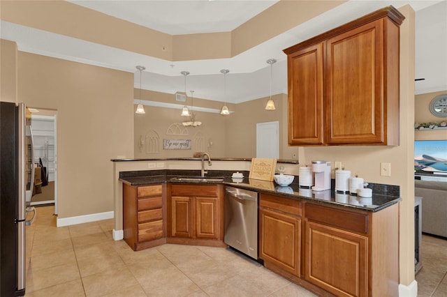 kitchen featuring pendant lighting, dark stone counters, sink, kitchen peninsula, and appliances with stainless steel finishes