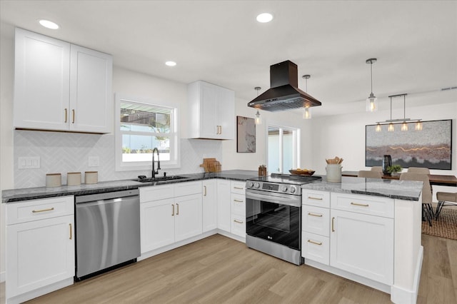 kitchen with sink, kitchen peninsula, island exhaust hood, decorative light fixtures, and appliances with stainless steel finishes