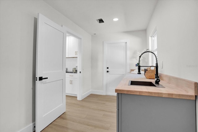 kitchen with sink, light hardwood / wood-style floors, and white cabinetry