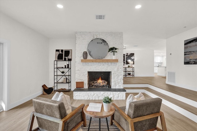 living room with light wood-type flooring and a stone fireplace