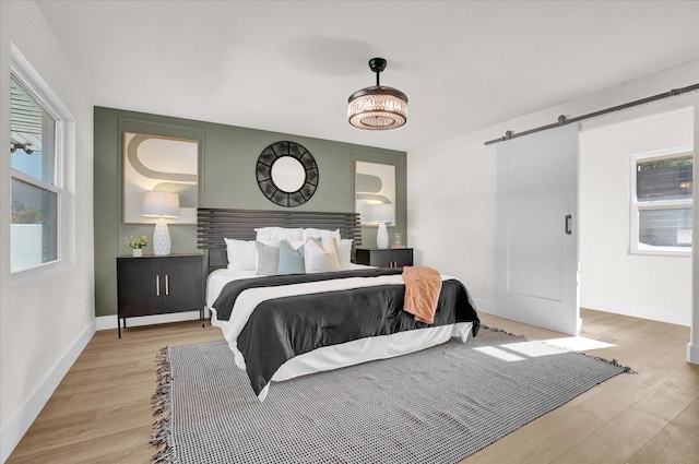 bedroom featuring light hardwood / wood-style flooring, a barn door, and multiple windows