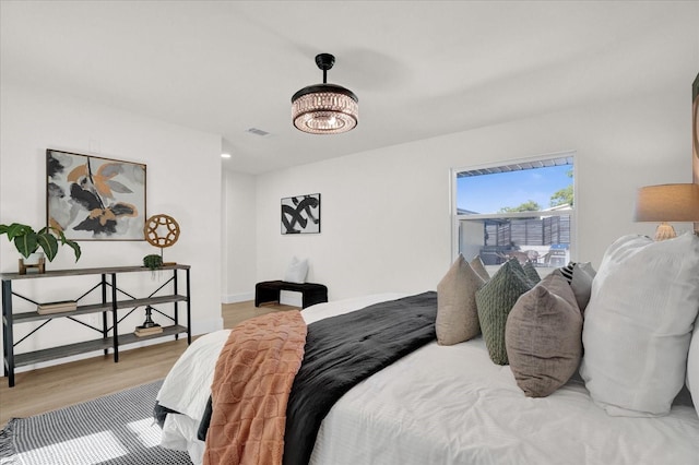 bedroom with a chandelier and hardwood / wood-style floors