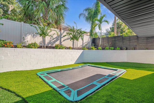 view of property's community with a trampoline and a yard