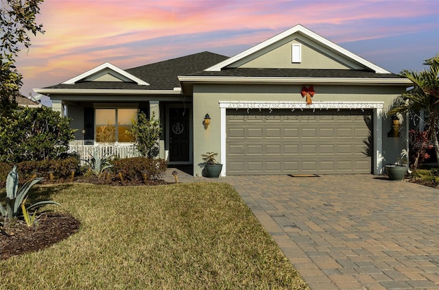 view of front of property featuring covered porch, a garage, and a lawn