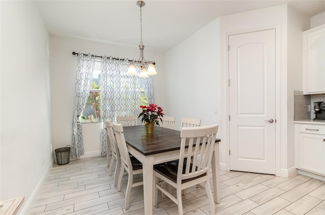 dining space with light hardwood / wood-style floors and a notable chandelier