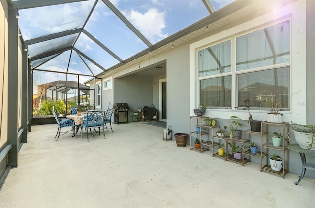 view of patio featuring glass enclosure and a grill