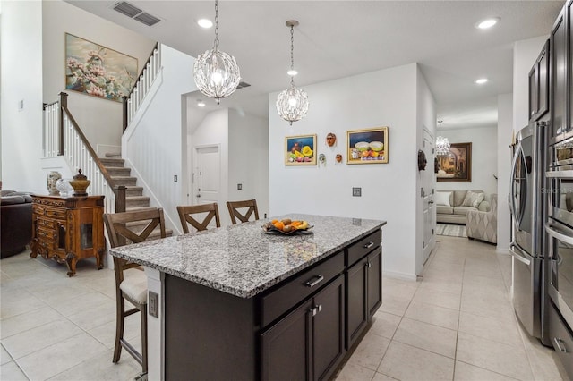 kitchen featuring light stone counters, light tile patterned floors, a kitchen breakfast bar, a kitchen island, and pendant lighting