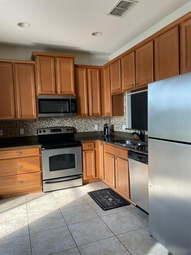 kitchen with decorative backsplash, stainless steel appliances, light tile patterned flooring, and sink