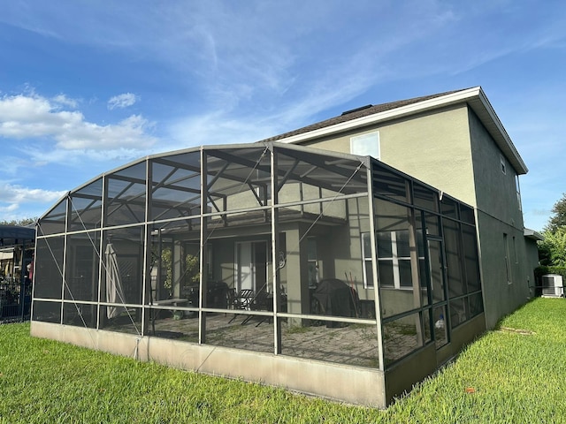 rear view of house with central air condition unit, a lanai, and a lawn