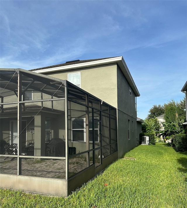 view of home's exterior with a yard, glass enclosure, and cooling unit