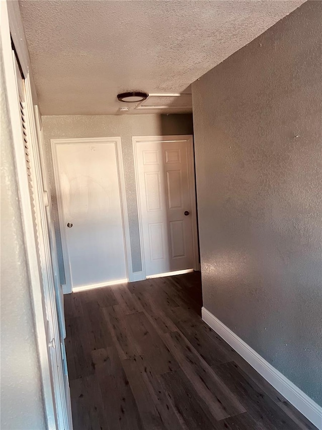 hall featuring a textured ceiling and dark wood-type flooring