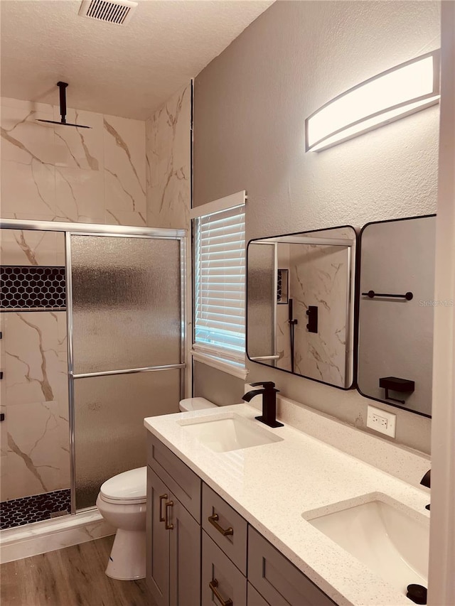 bathroom featuring wood-type flooring, vanity, toilet, and a shower with shower door