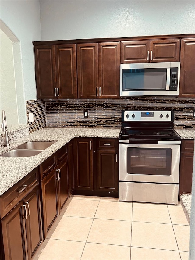 kitchen with decorative backsplash, appliances with stainless steel finishes, light tile patterned flooring, and sink