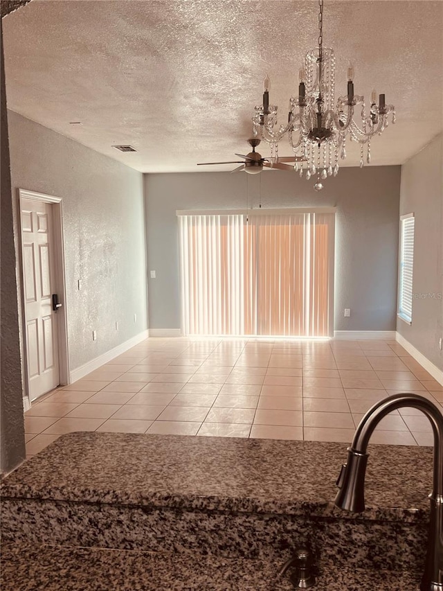 tiled empty room featuring a textured ceiling and ceiling fan with notable chandelier