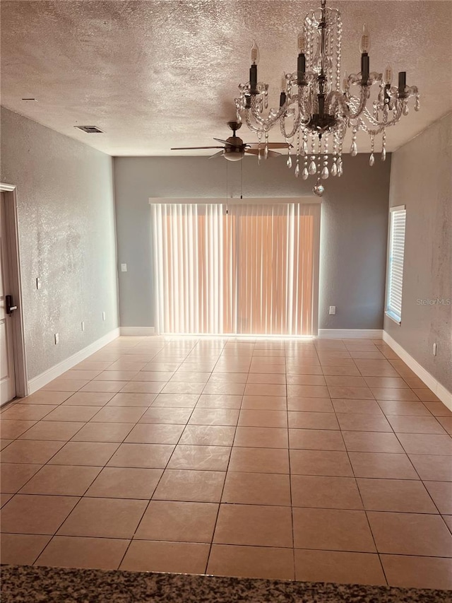 unfurnished room with a textured ceiling, ceiling fan with notable chandelier, and tile patterned flooring