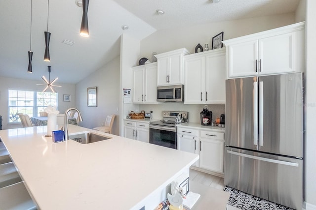 kitchen featuring lofted ceiling, sink, a kitchen island with sink, white cabinetry, and stainless steel appliances