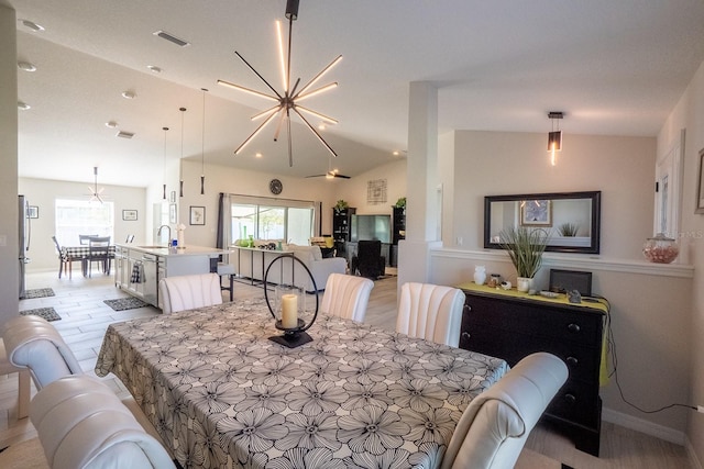 dining area with an inviting chandelier, vaulted ceiling, sink, and light hardwood / wood-style flooring