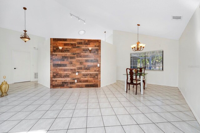 unfurnished room featuring light tile patterned flooring, wooden walls, high vaulted ceiling, and a notable chandelier