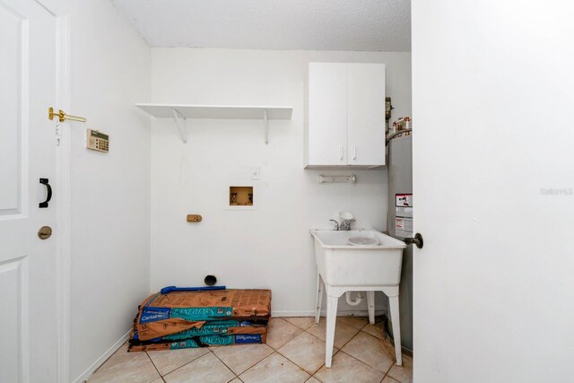 washroom with washer hookup, a textured ceiling, cabinets, and light tile patterned floors