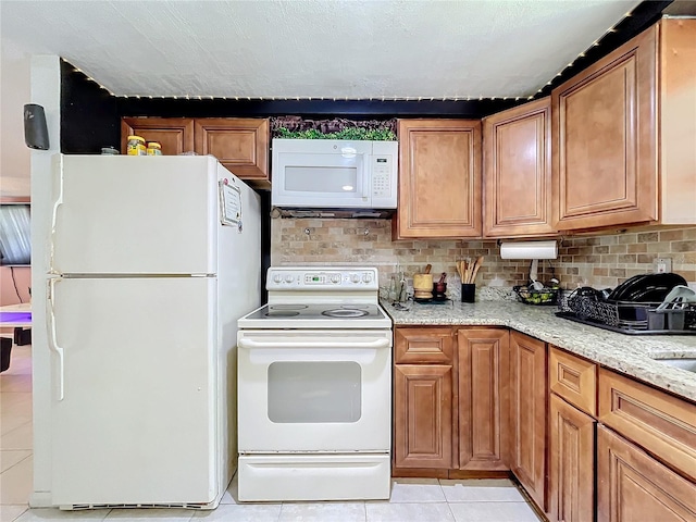 kitchen with tasteful backsplash, white appliances, light stone countertops, light tile patterned floors, and a textured ceiling