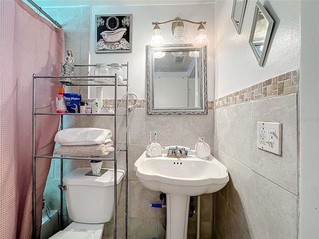 bathroom with tile walls, toilet, and a shower with shower curtain