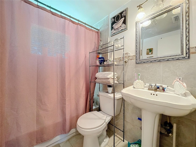 bathroom with curtained shower, tile walls, toilet, and tile patterned floors