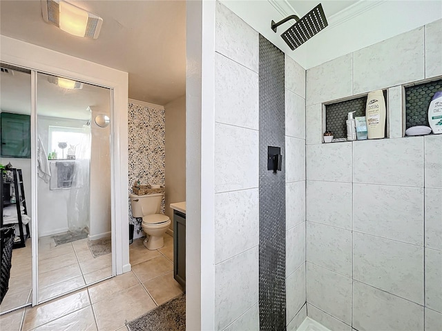 bathroom featuring a tile shower, tile patterned flooring, crown molding, vanity, and toilet