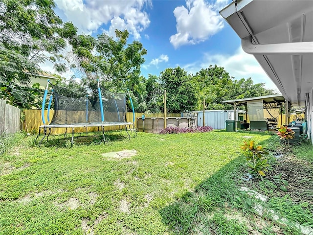 view of yard featuring a trampoline and a shed