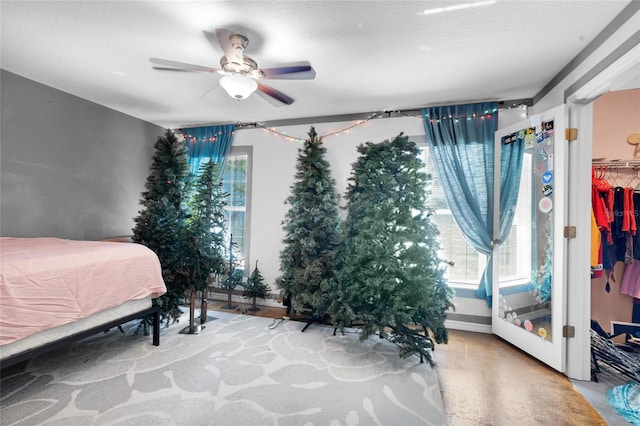 bedroom with a textured ceiling, a walk in closet, a closet, and ceiling fan