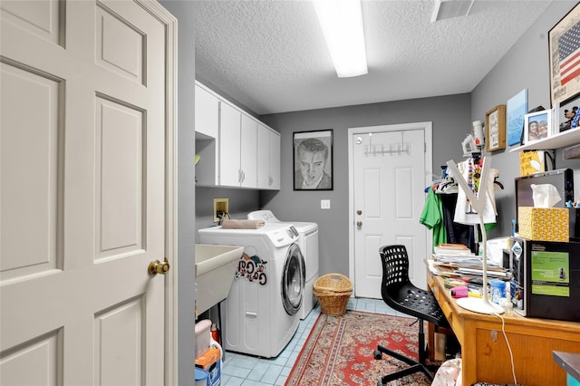 laundry area featuring washer and clothes dryer, cabinets, a textured ceiling, and light tile patterned flooring