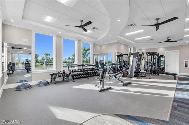 gym featuring ornamental molding, a tray ceiling, and ceiling fan